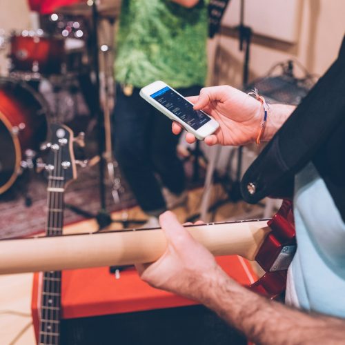 close-up-man-hand-guitarist-using-smartphone-4KHZ4BR